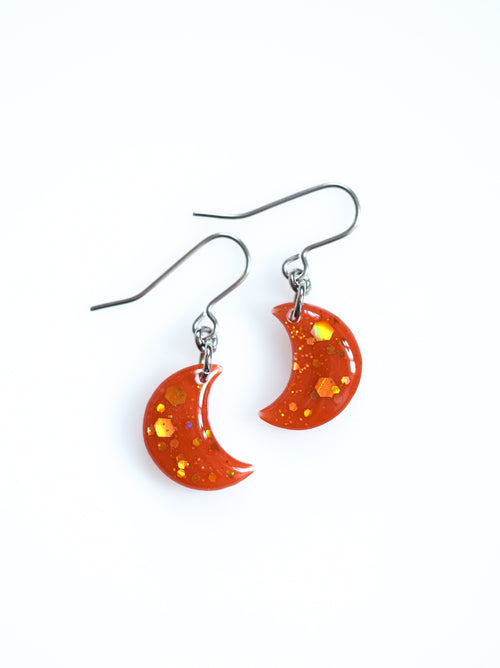 Artemis moon drop earrings in orange with holographic colour shifting glitter on a white background