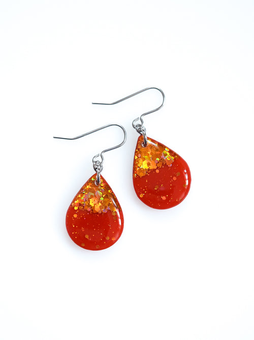 Clio earrings in orange with holographic colour shifting glitter on a white background