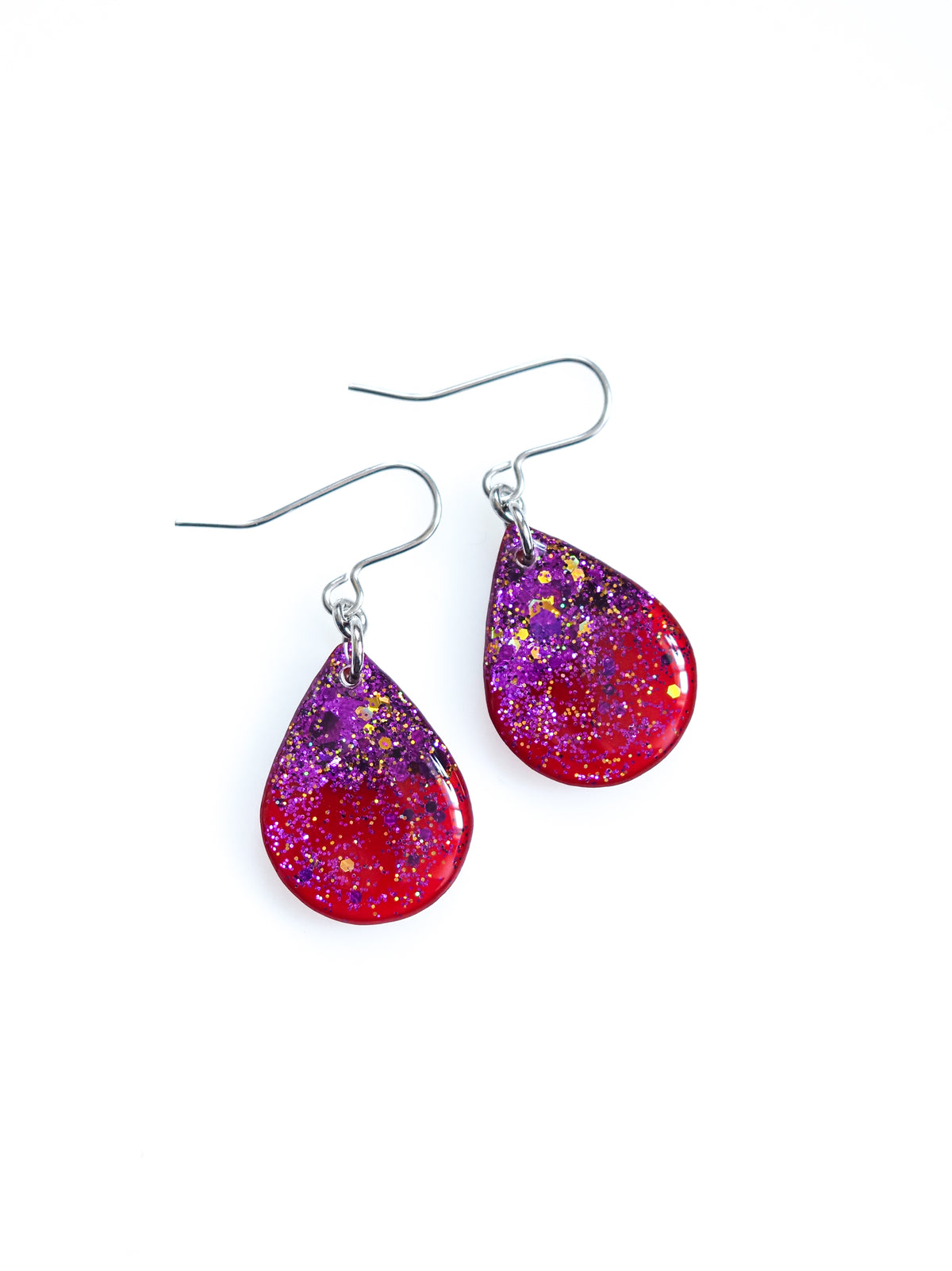 Clio drop earrings in red with purple and gold holographic colour shifting glitter on a white background