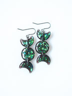 Hecate triple moon drop earrings in transparent black with iridescent glitter on a white background