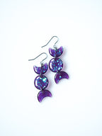Hecate triple moon drop earrings in transparent purple with iridescent glitter on a white background
