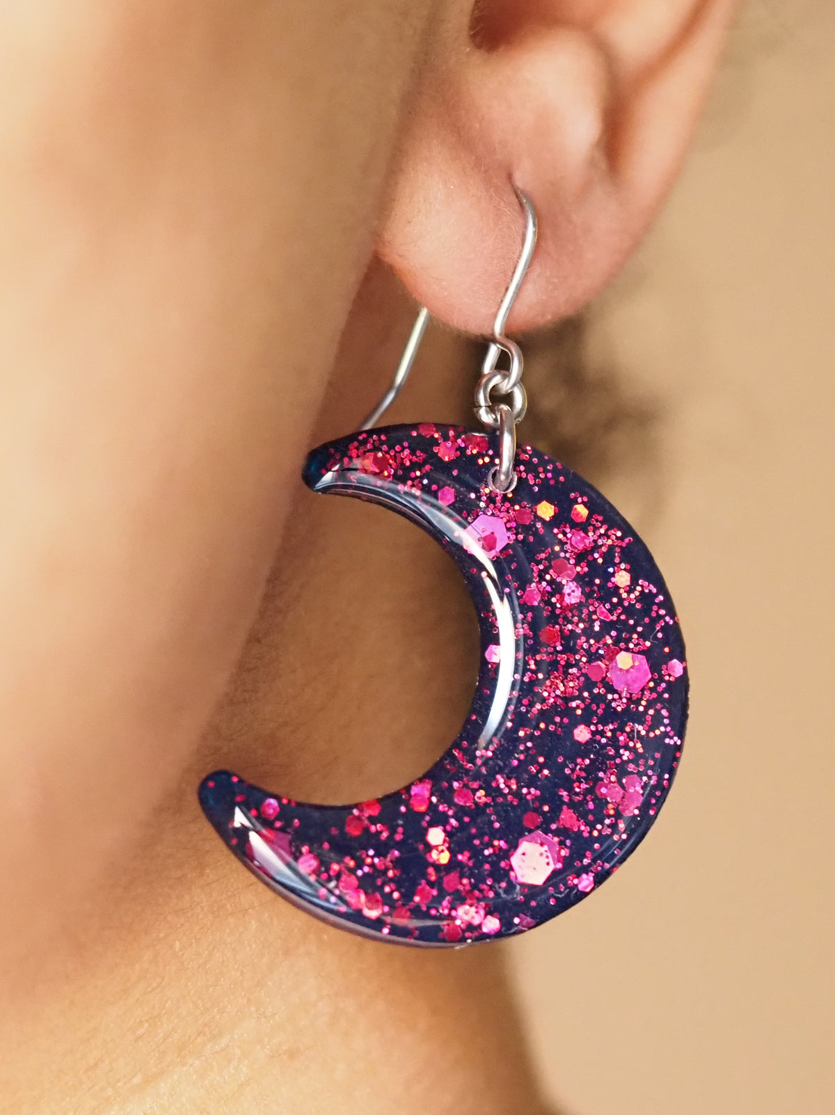 A pair of Luna large moon drop earrings, shown being worn. The wearers face is out of shot with hair pulled back to display the earring. 