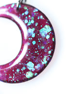 Macro close up of the Luna moon drop earrings in transparent purple with iridescent glitter on a white background