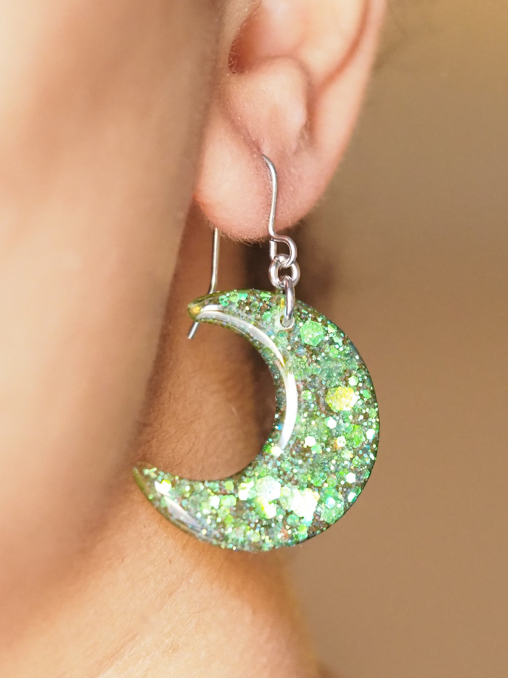 A pair of Luna small moon drop earrings, shown being worn. The wearers face is out of shot with hair pulled back to display the earring. 