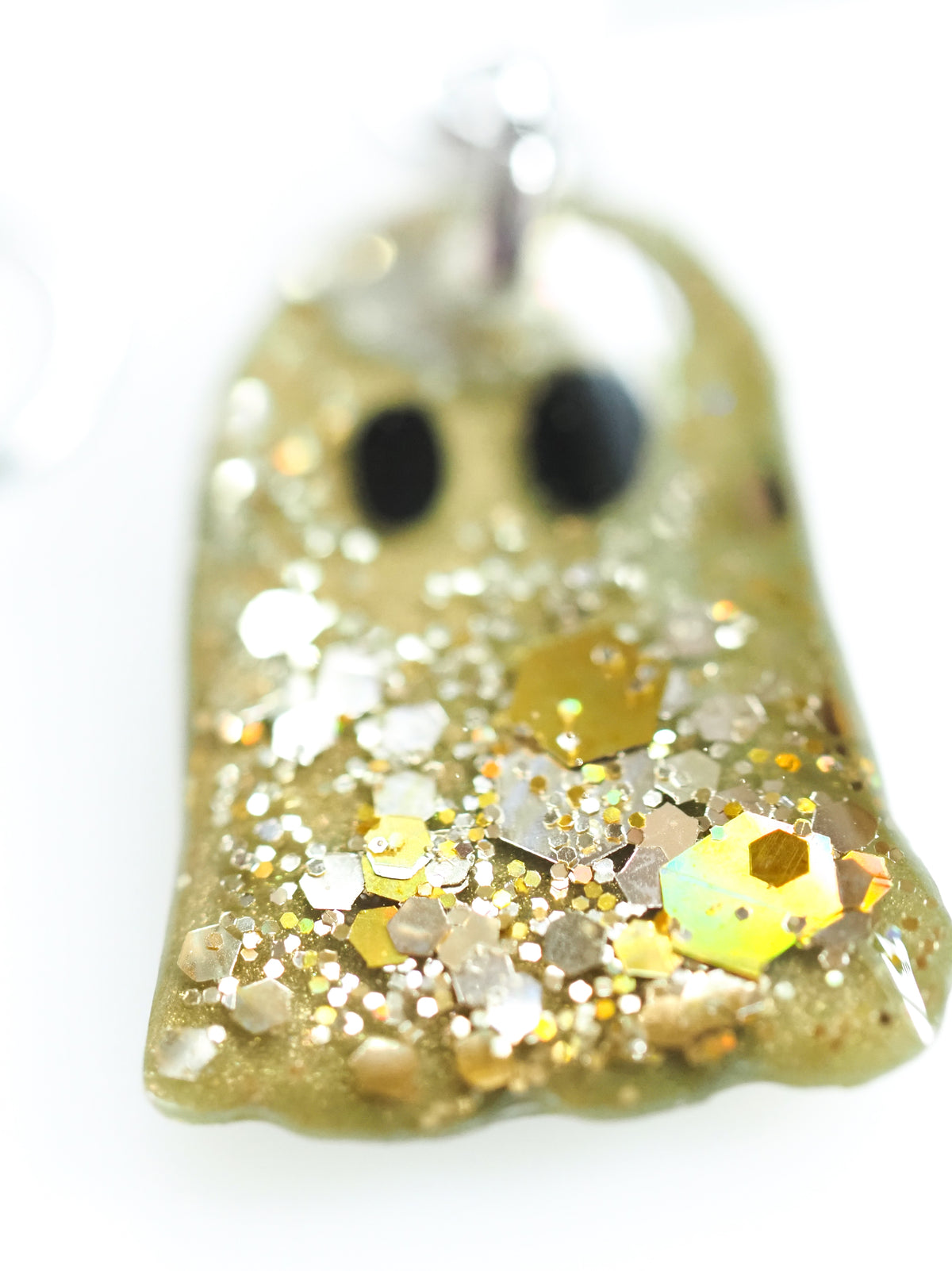 Close up of the Melinoë ghost drop earrings in autumn green with gold holographic colour shifting glitter on a white background