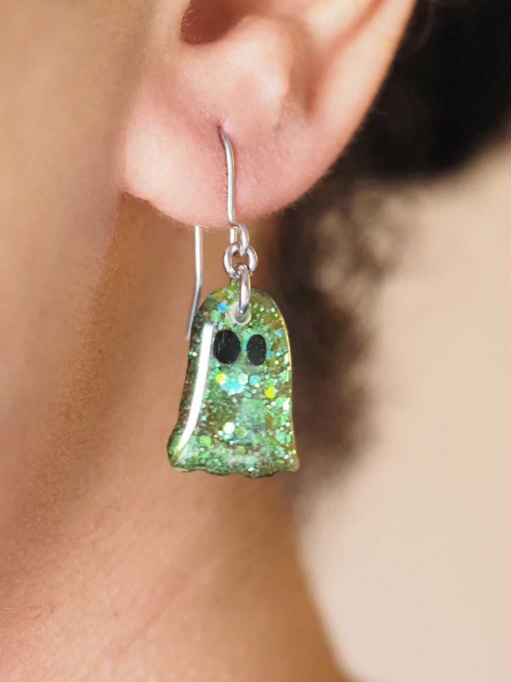A pair of Melinoe ghost drop earrings, shown being worn. The wearers face is out of shot with hair pulled back to display the earring. 