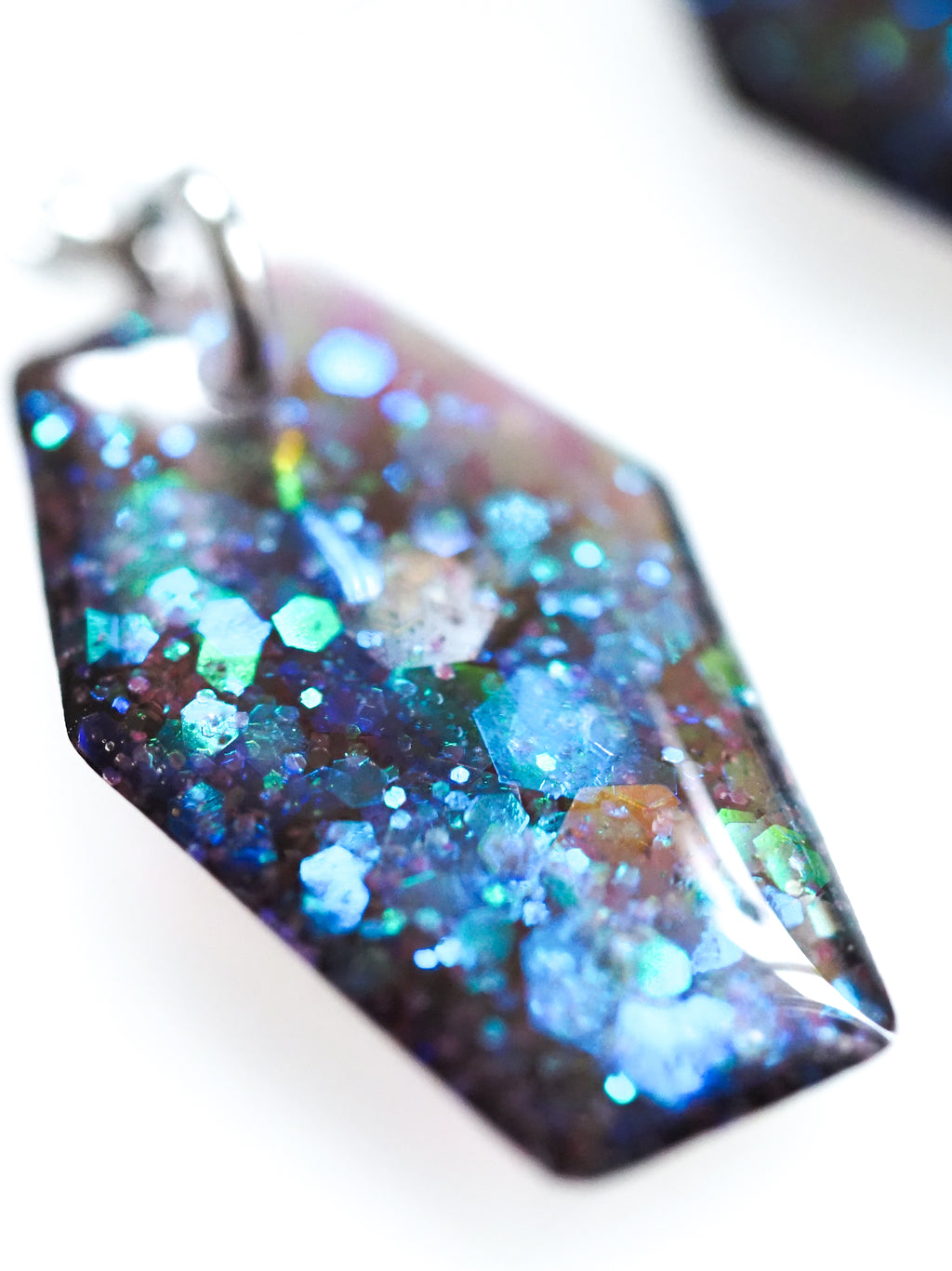 Close up of the Morrigan coffin earrings in transparent black with iridescent colour shifting glitter on a white background