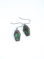 Morrigan coffin earrings in transparent black with iridescent colour shifting glitter on a white background