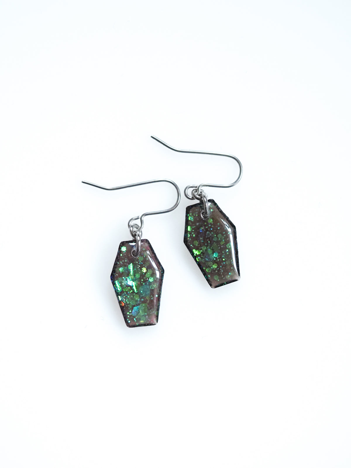 Morrigan coffin earrings in transparent black with iridescent colour shifting glitter on a white background