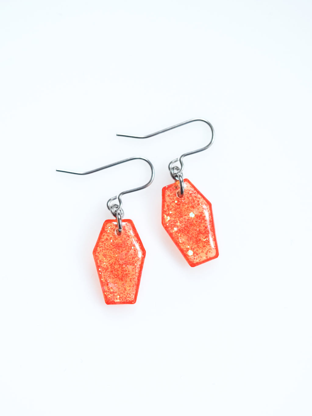 Morrigan coffin earrings in transparent orange with iridescent colour shifting glitter on a white background