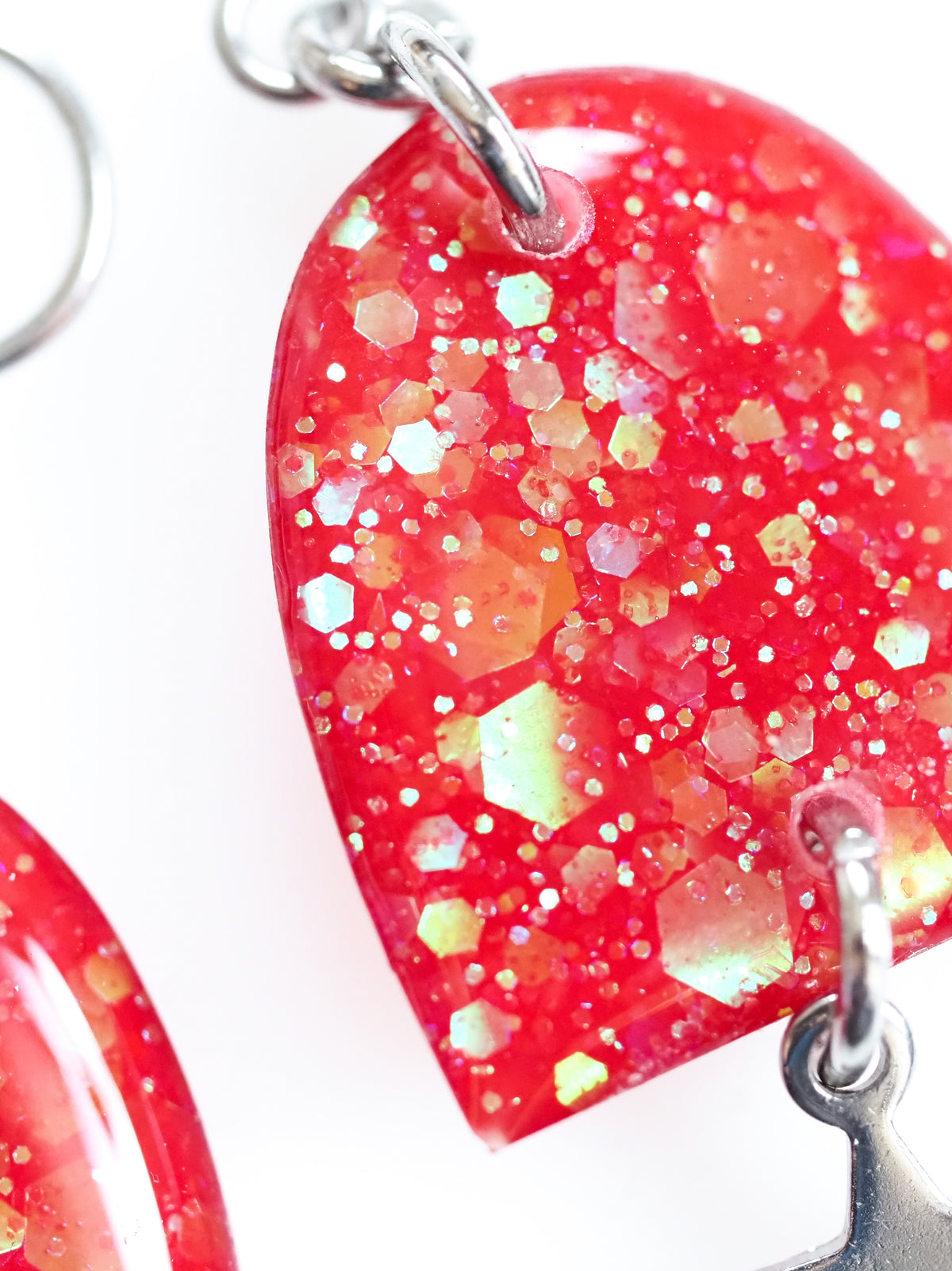 Close up of the Nyx drop earrings in red with iridescent colour shifting glitter on a white background