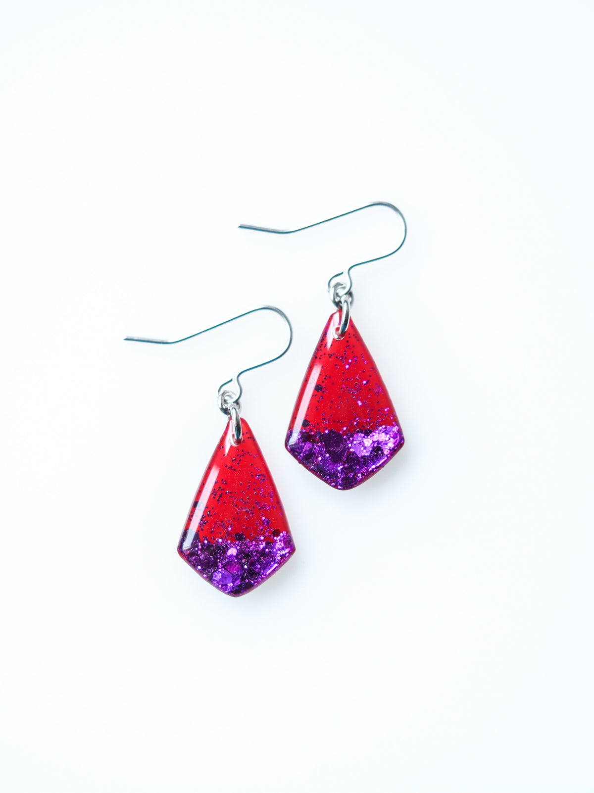 Persephone drop earrings in red with purple metallic glitter on a white background