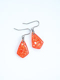 Persephone drop earrings in orange with iridescent colour shifting glitter on a white background