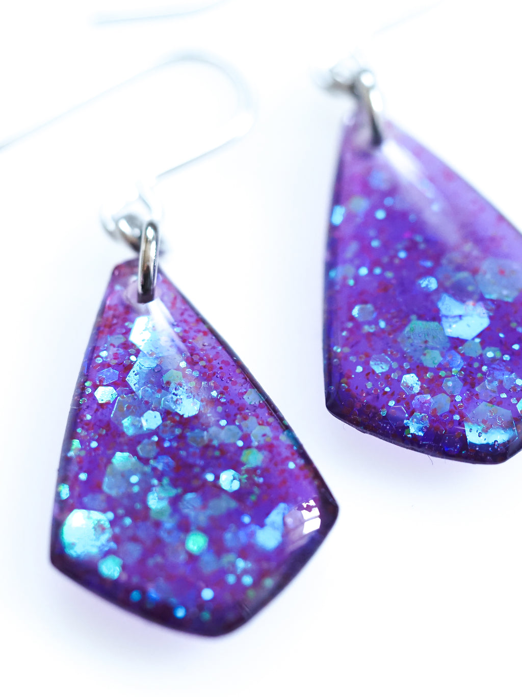 Close up of the Persephone drop earrings in purple with iridescent colour shifting glitter on a white background