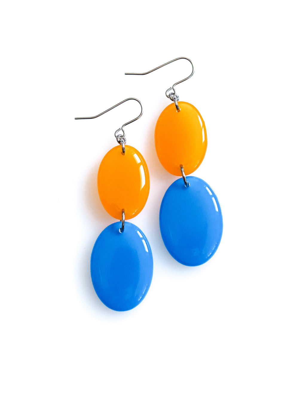 Duet resin drop earrings from the Chroma collection in translucent orange and bright blue on a white background