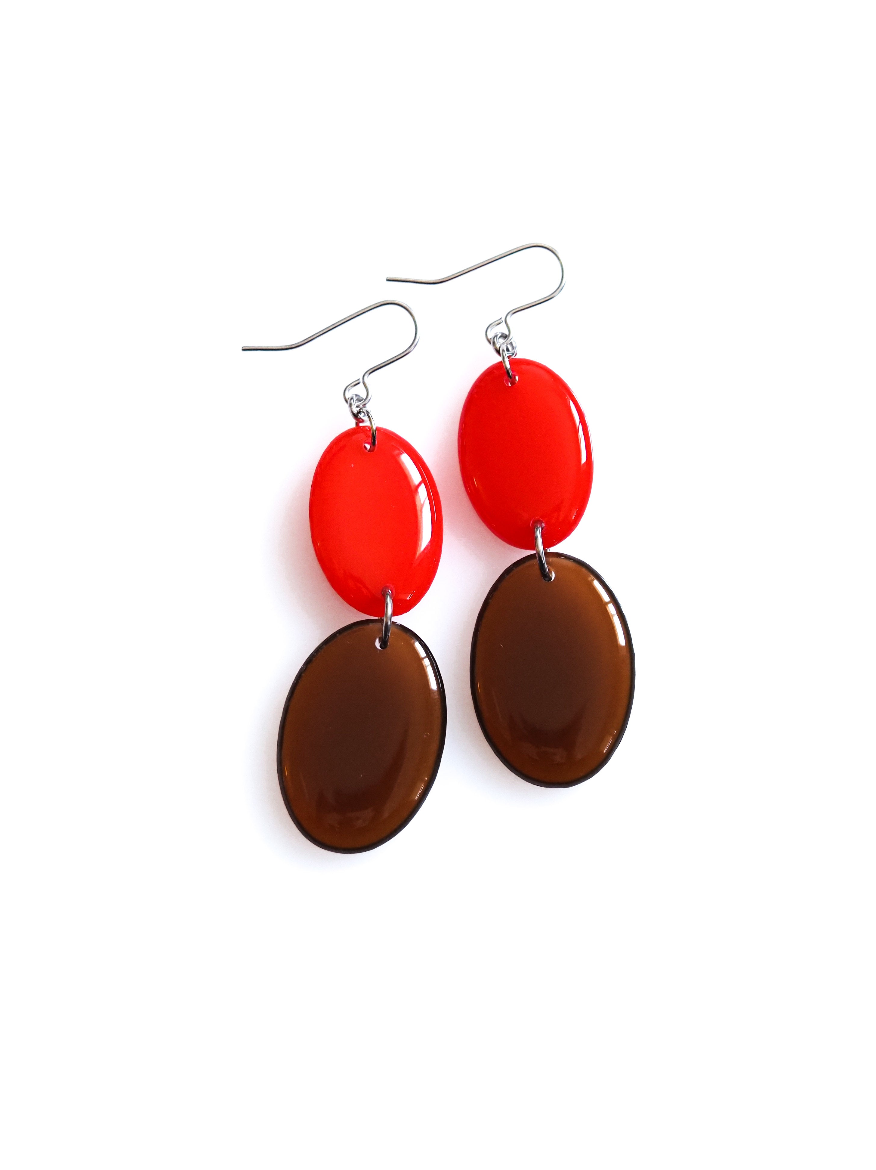 Duet resin drop earrings from the Chroma collection in red and transparent burnt umber on a white background