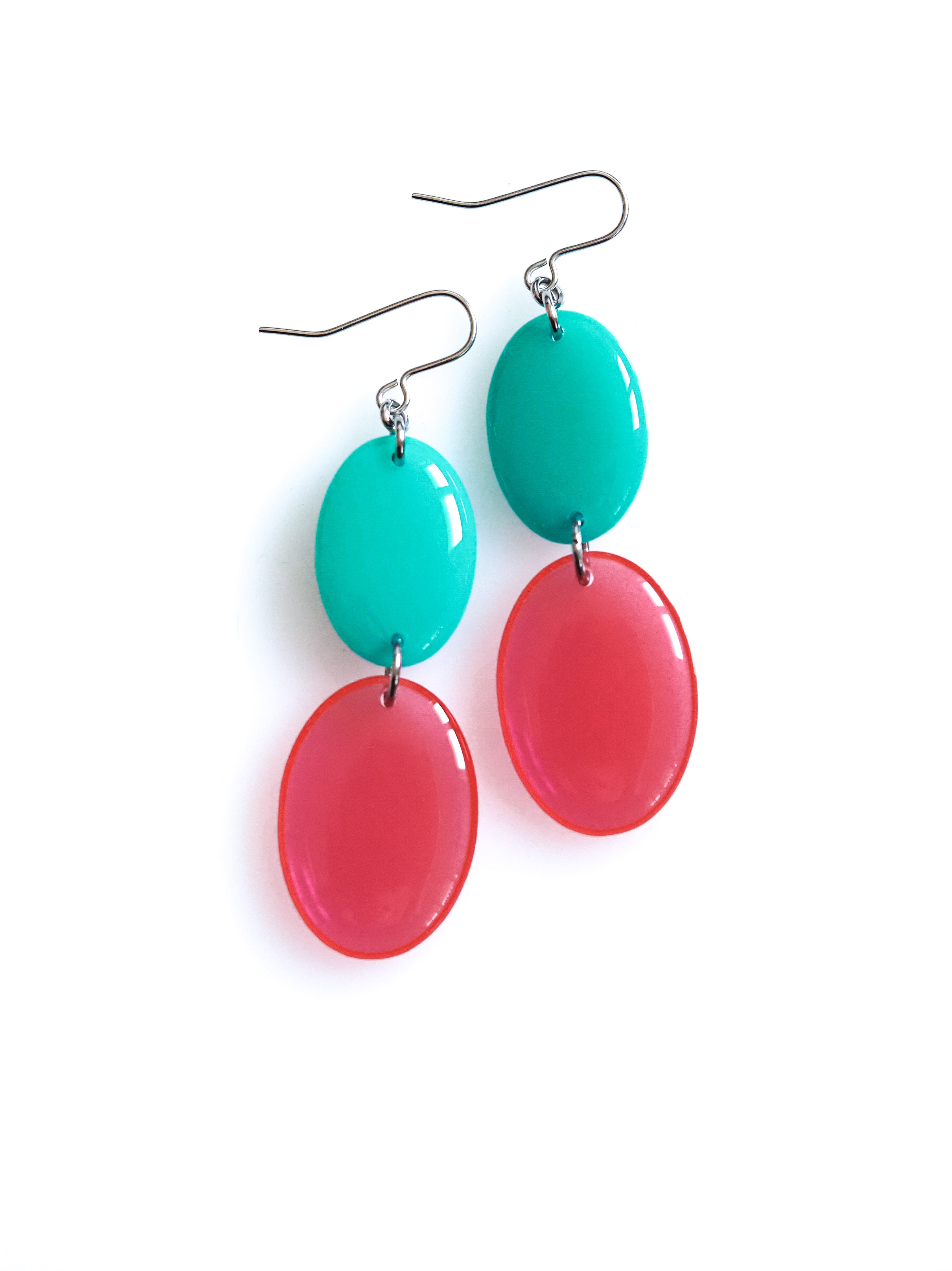 Duet resin drop earrings from the Chroma collection in turquoise and transparent red on a white background