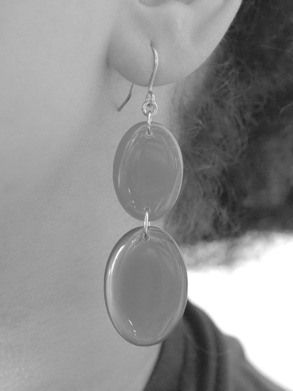 Close cropped greyscale image of the handmade Duet drop earrings being worn.