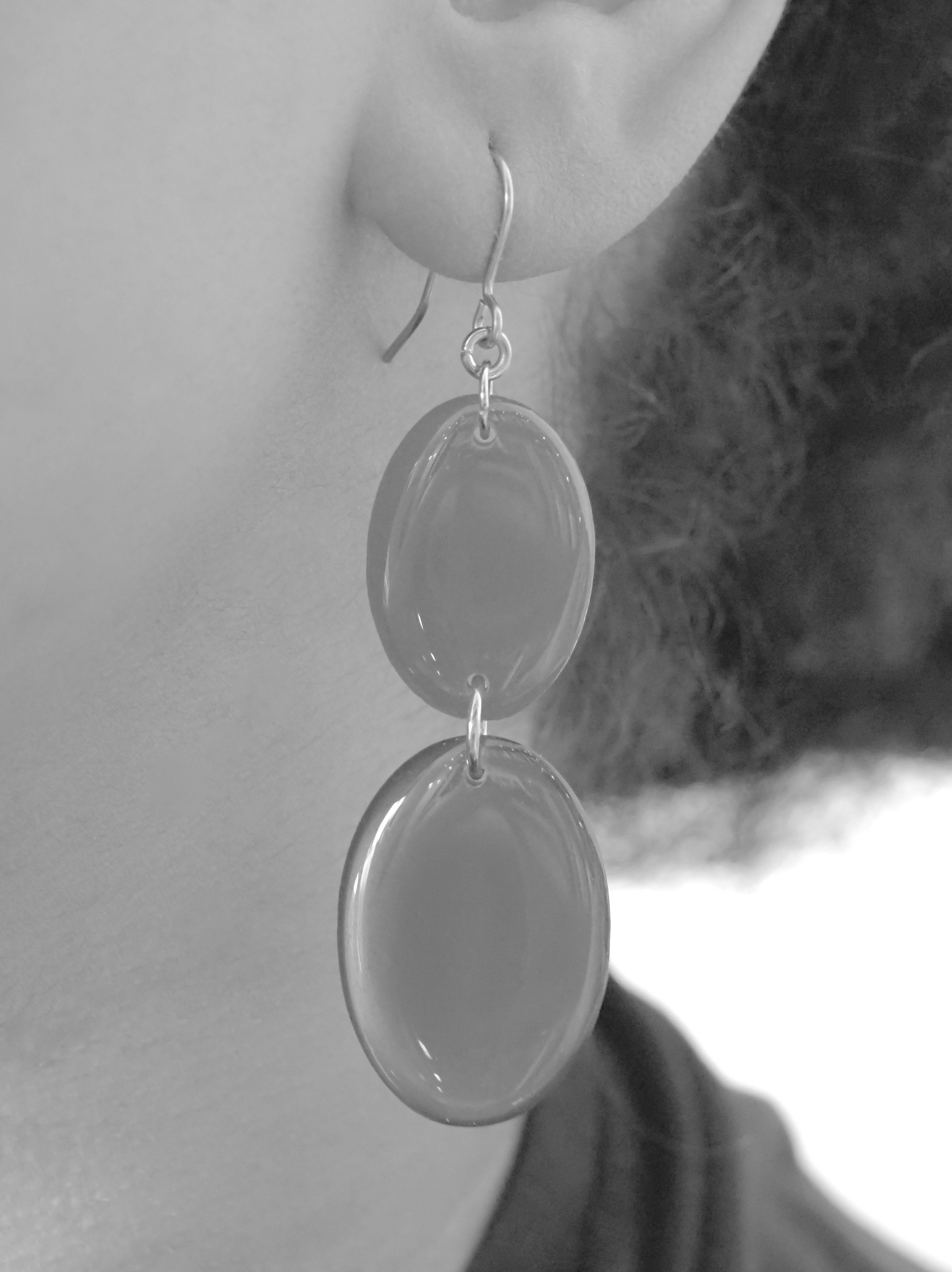 Close cropped greyscale image of the handmade Duet drop earrings being worn.