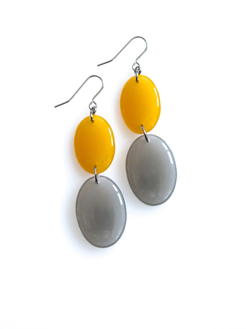 Duet resin drop earrings from the Chroma collection in translucent marigold and mist grey on a white background
