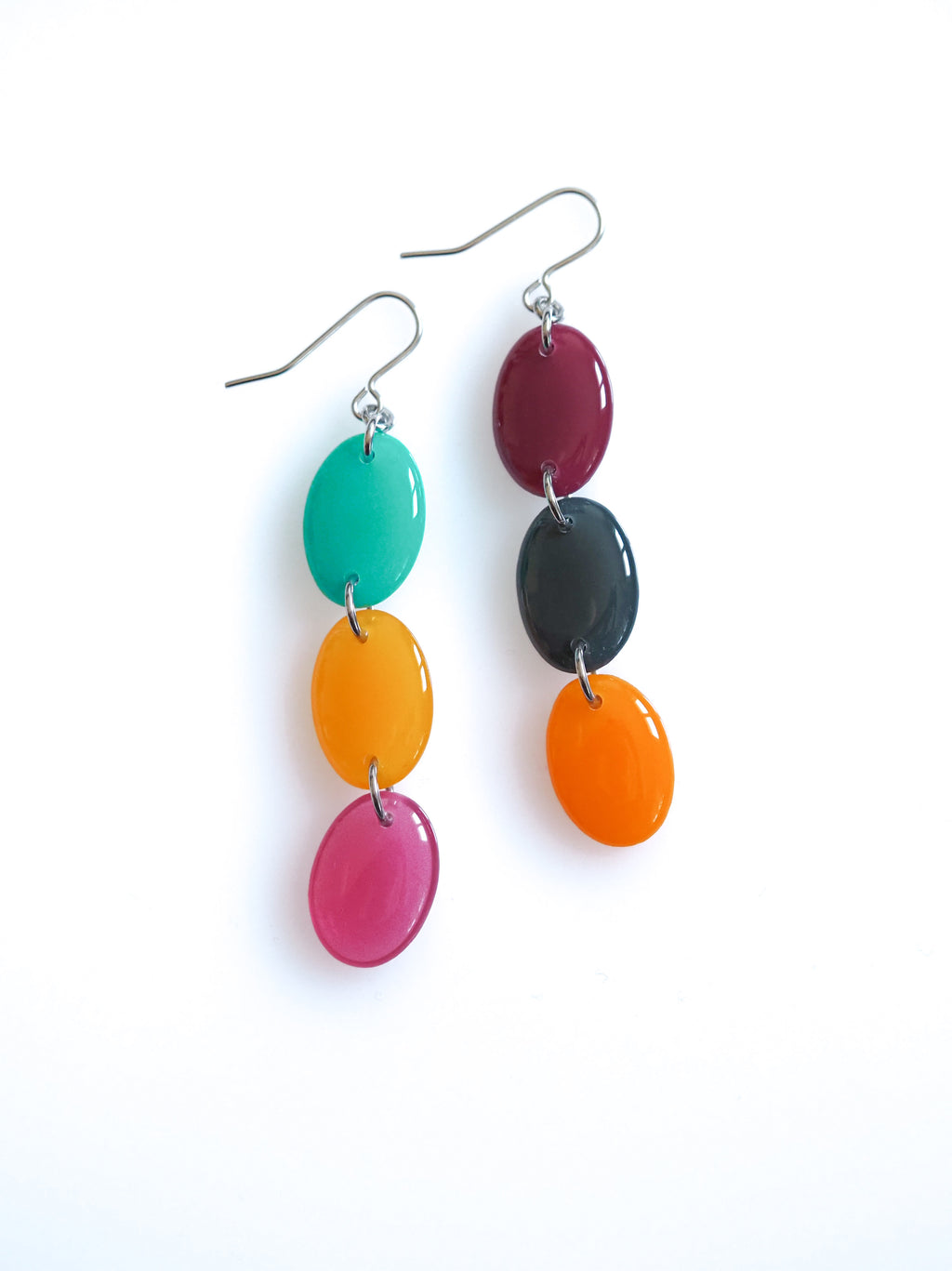 Sequence resin drop earrings from the Chroma collection in turquoise, translucent orange, orange, transparent mulberry, mulberry and petrol grey on a white background