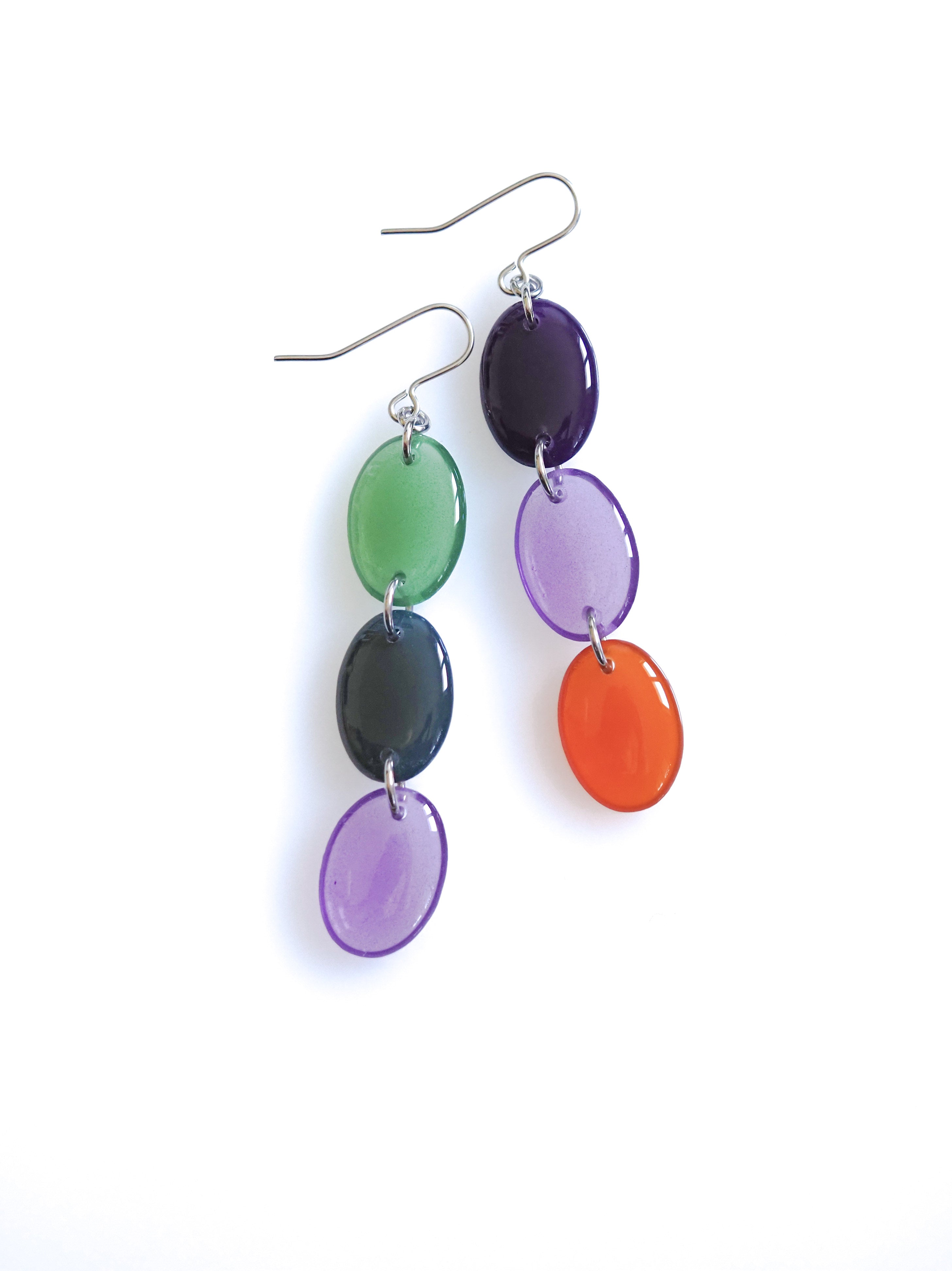 Sequence resin drop earrings from the Chroma collection in transparent forest green, petrol grey, transparent aubergine, aubergine and rust on a white background