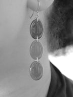 Close cropped greyscale image of the handmade Sequence drop earrings being worn.