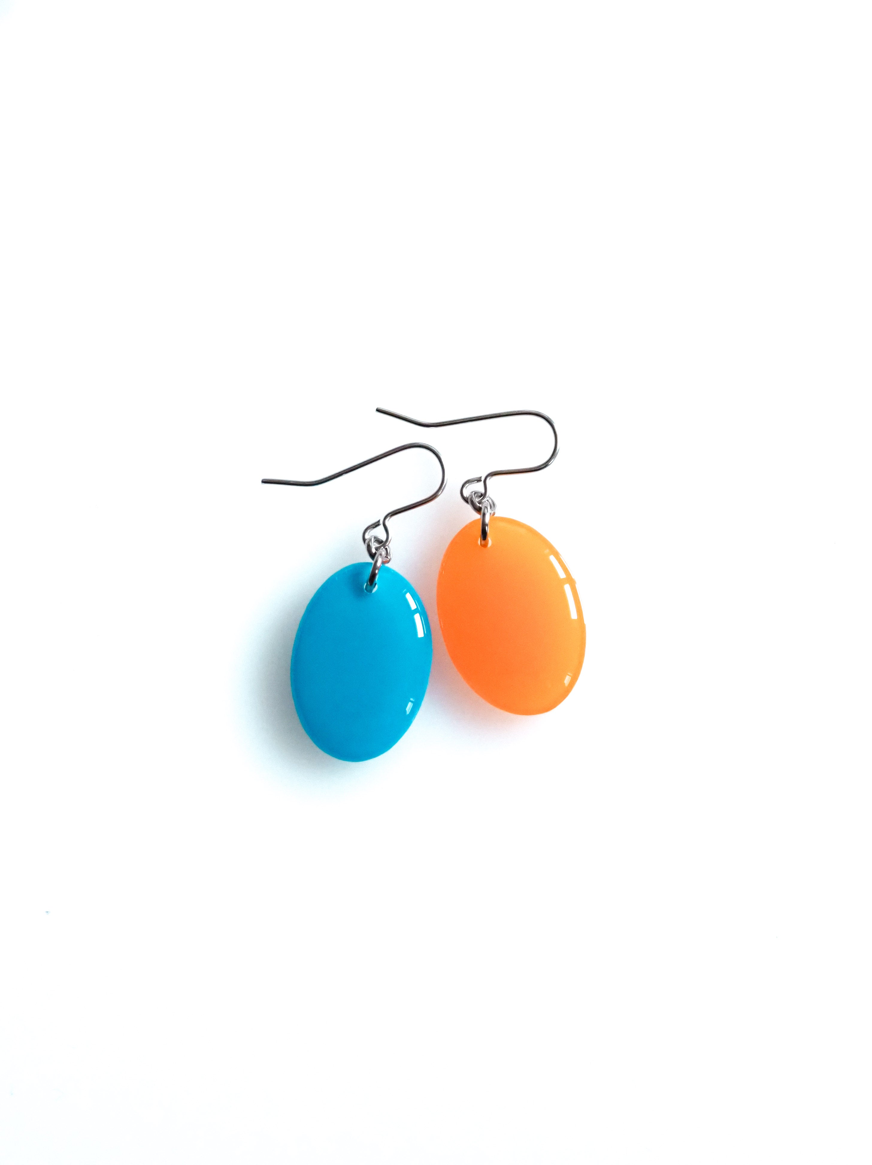 Solo resin drop earrings from the Chroma collection in bright blue and translucent orange on a white background