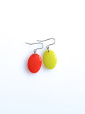 Solo resin drop earrings from the Chroma collection in red and electric lichen on a white background
