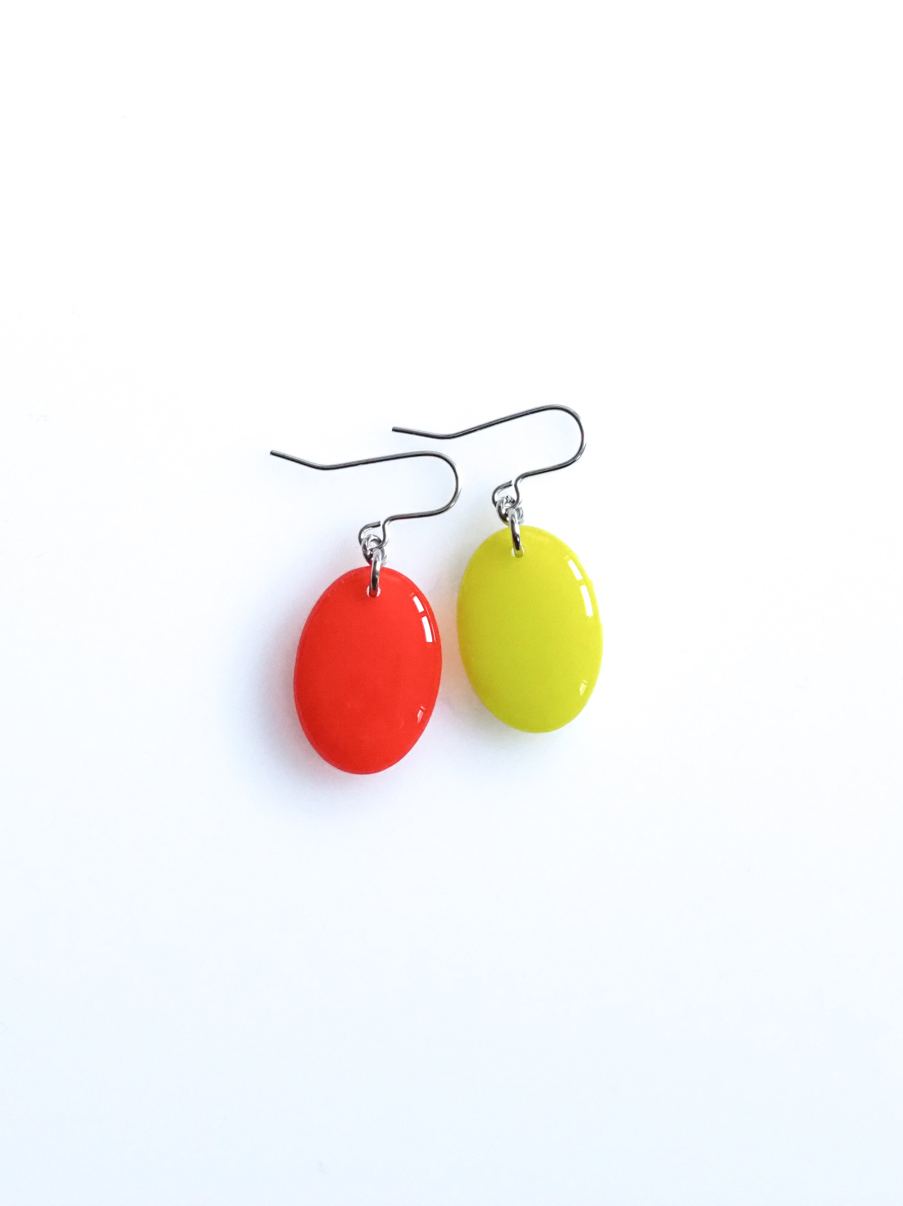 Solo resin drop earrings from the Chroma collection in red and electric lichen on a white background