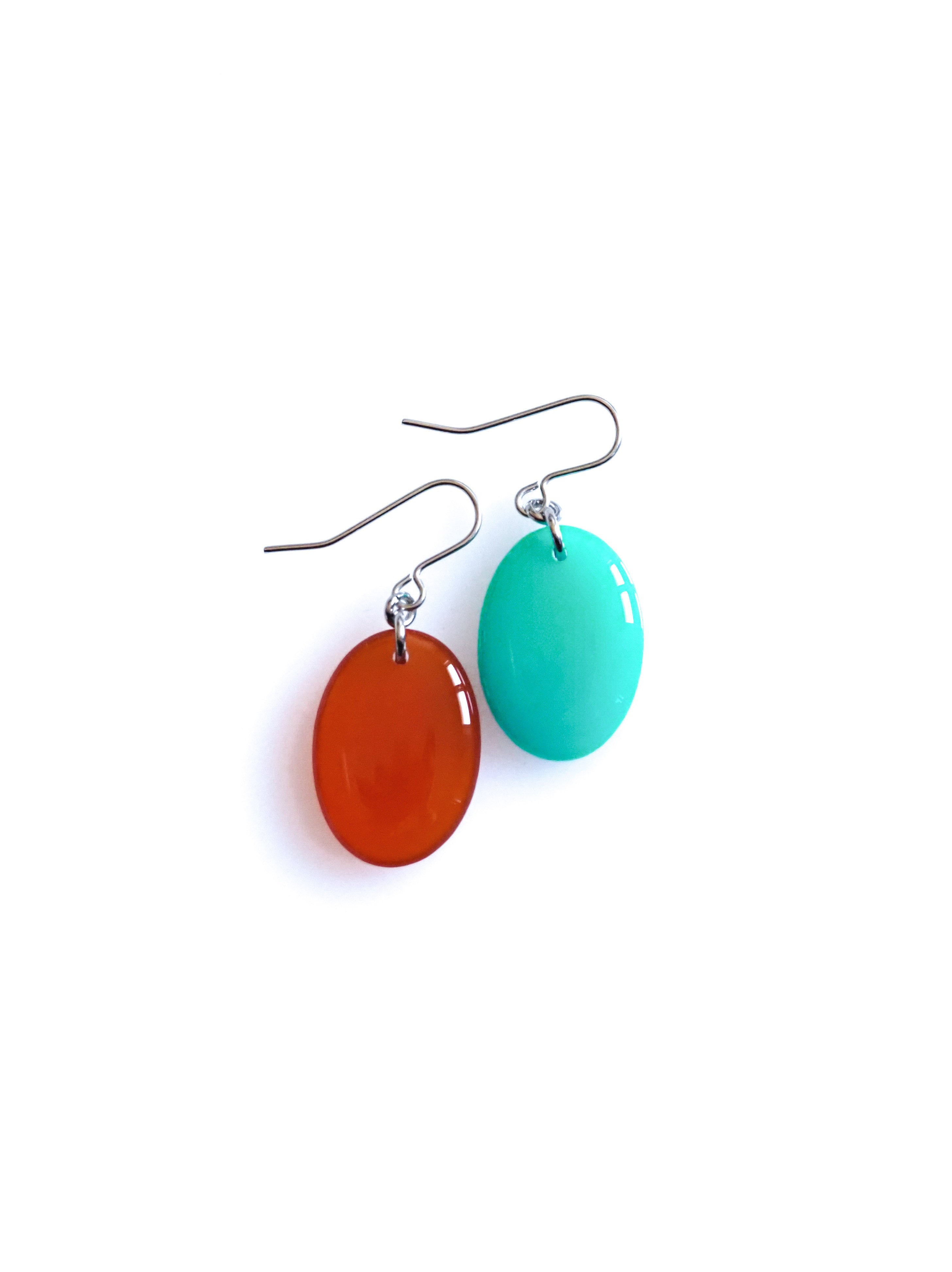 Solo resin drop earrings from the Chroma collection in transparent rust and turquoise on a white background