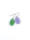 Solo resin drop earrings from the Chroma collection in transparent forest green and transparent aubergine on a white background