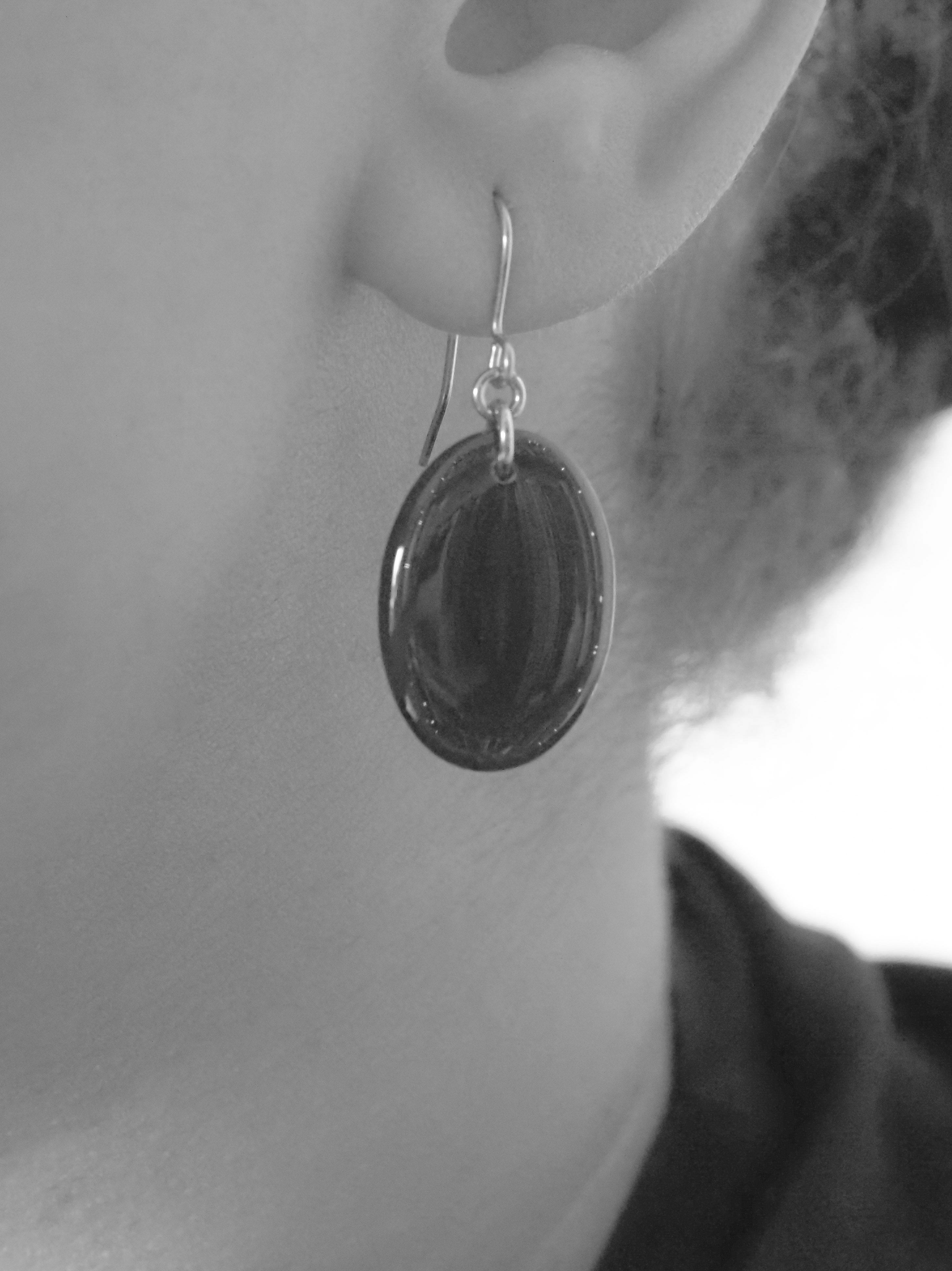 Close cropped greyscale image of the handmade Solo drop earrings being worn.