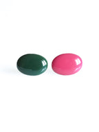 Solo resin stud earrings from the Chroma collection in forest green and candy pink on a white background