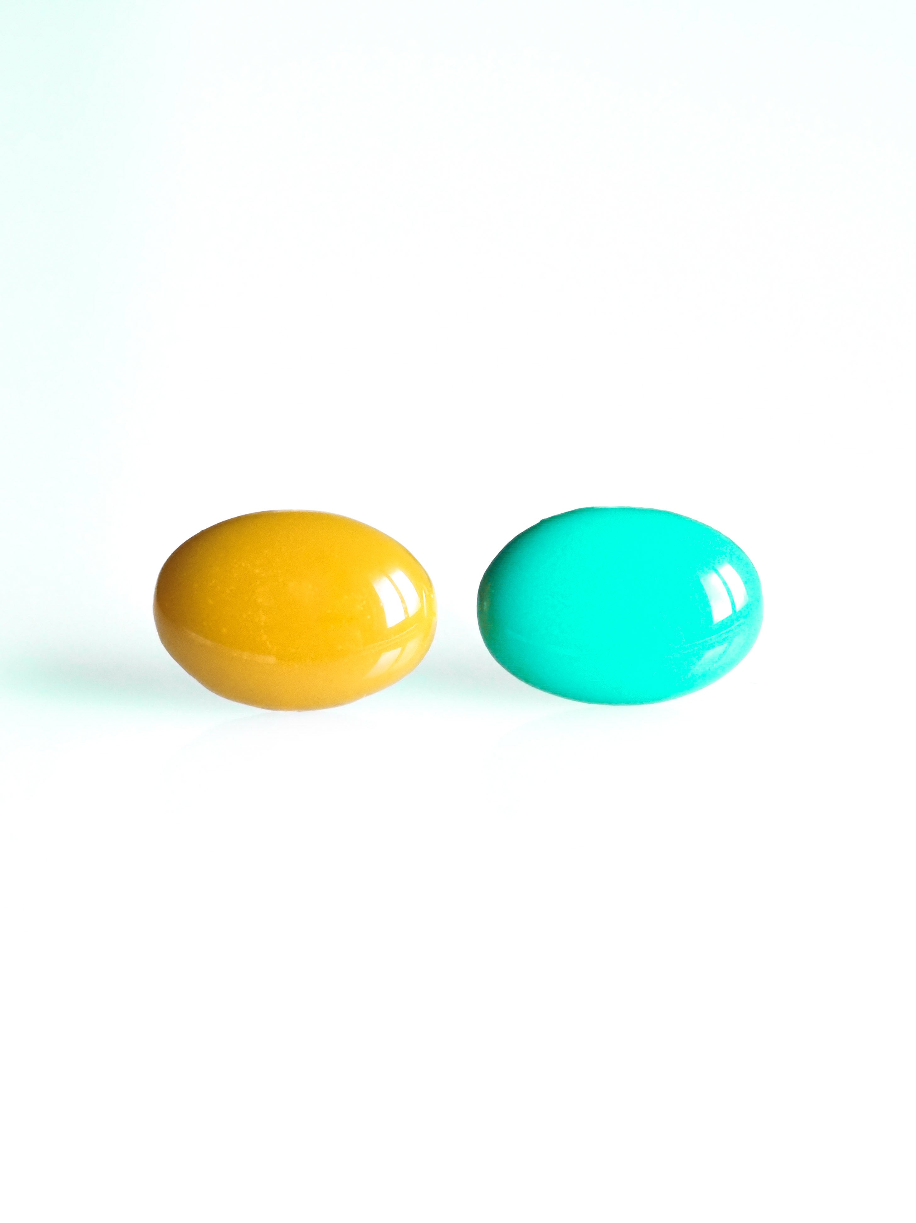 Solo resin stud earrings from the Chroma collection in marigold yellow and turquoise on a white background