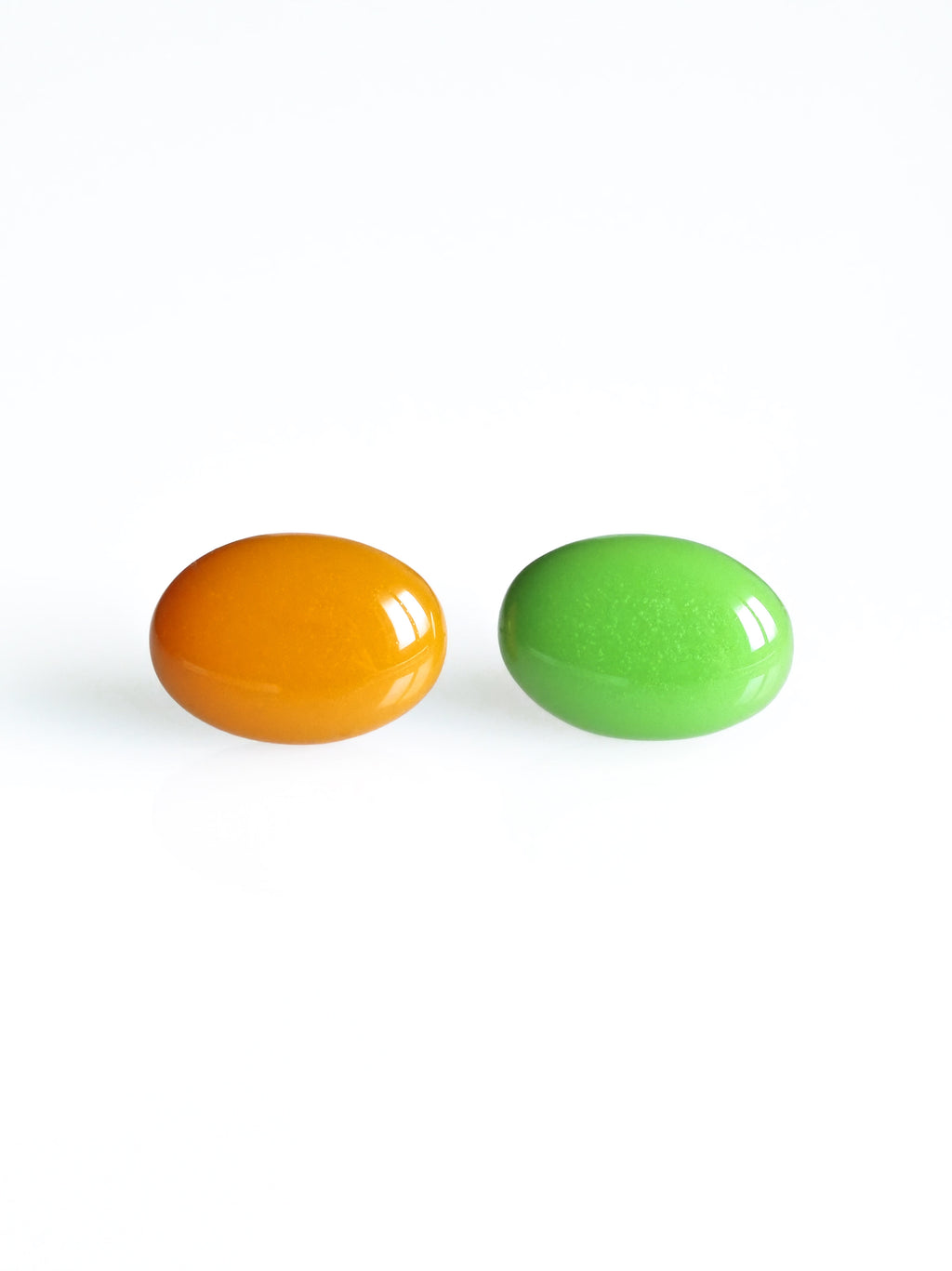Solo resin stud earrings from the Chroma collection in orange and grass green on a white background