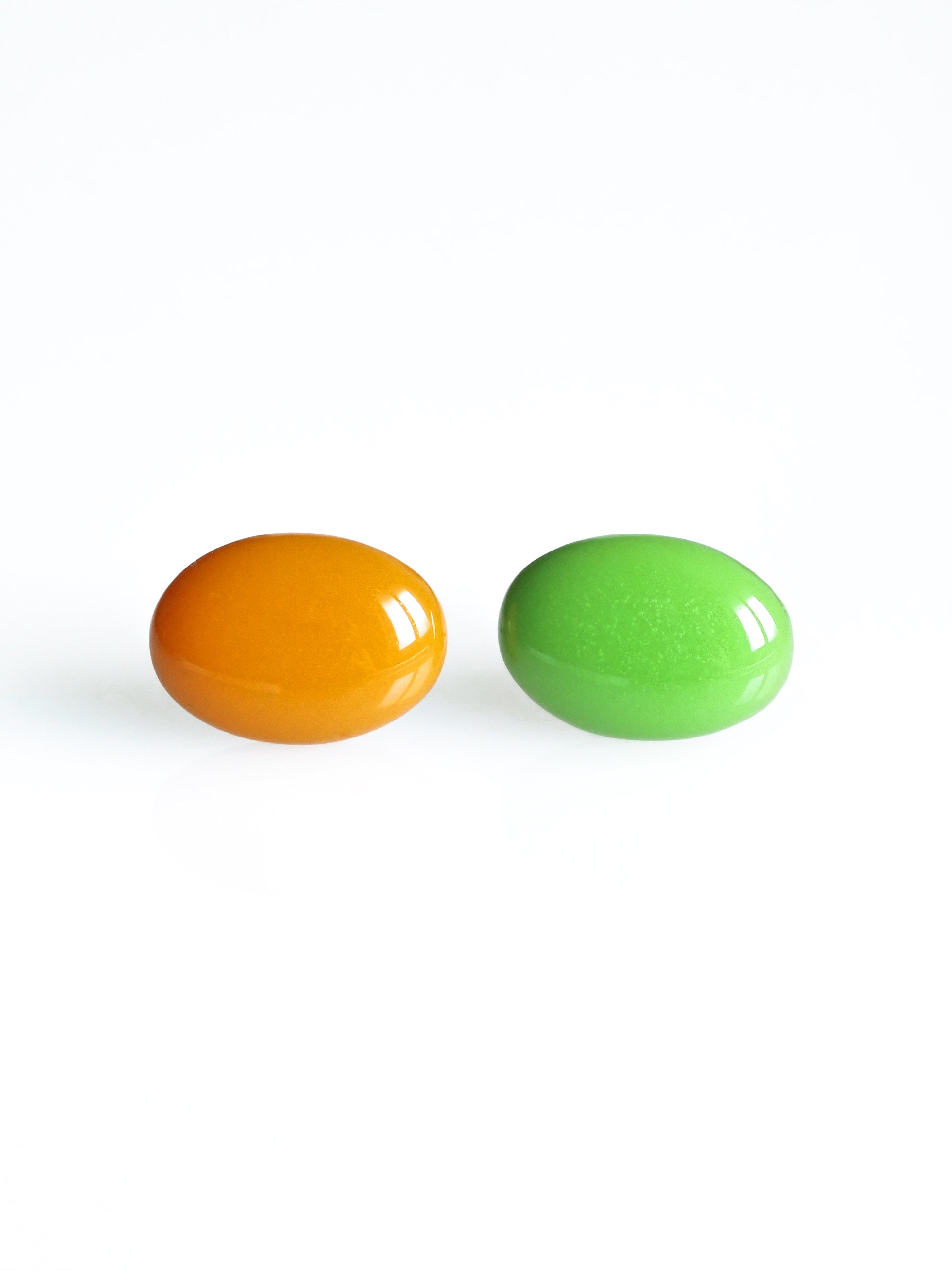 Solo resin stud earrings from the Chroma collection in orange and grass green on a white background