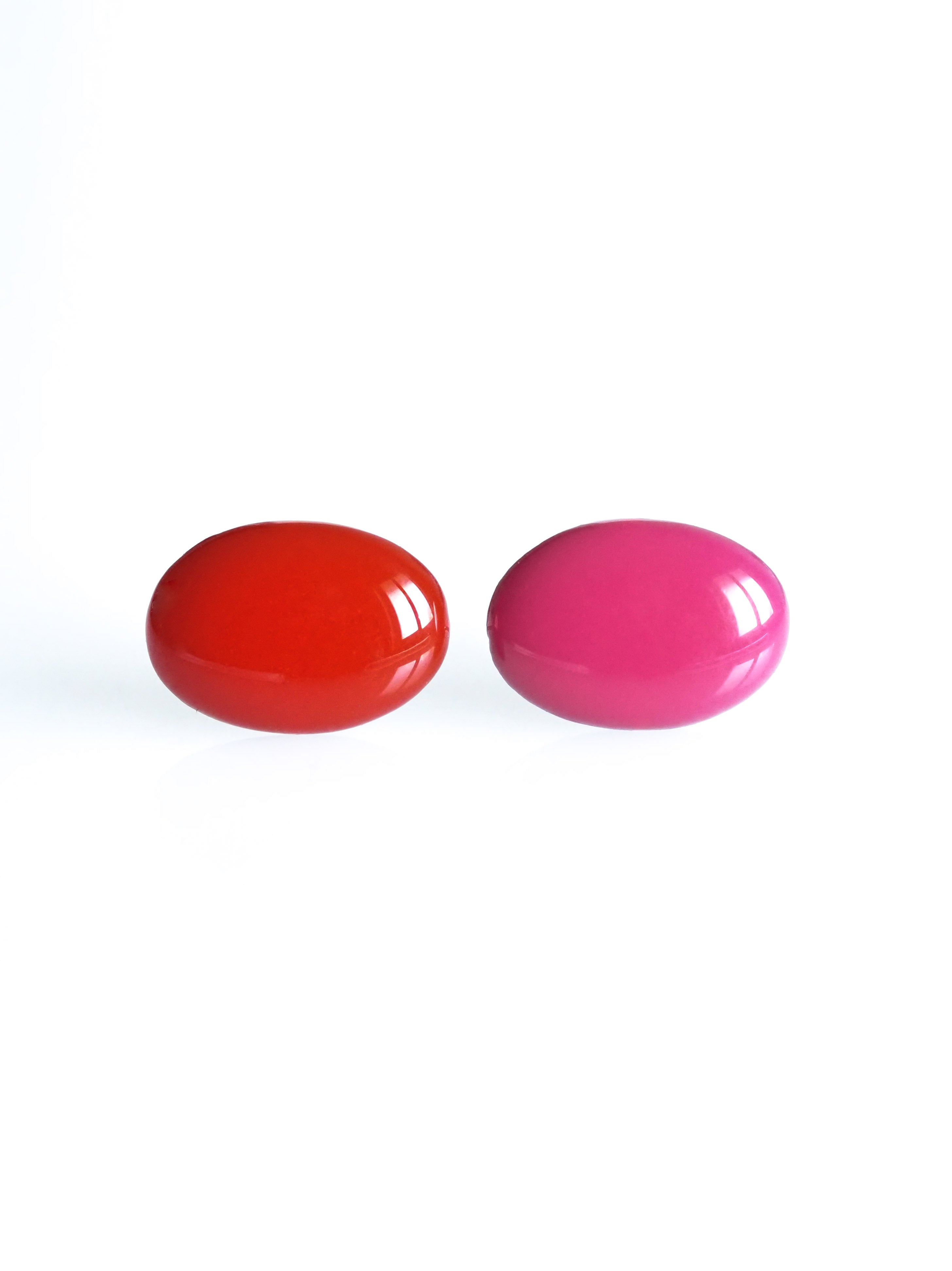 Solo resin stud earrings from the Chroma collection in red and candy pink on a white background