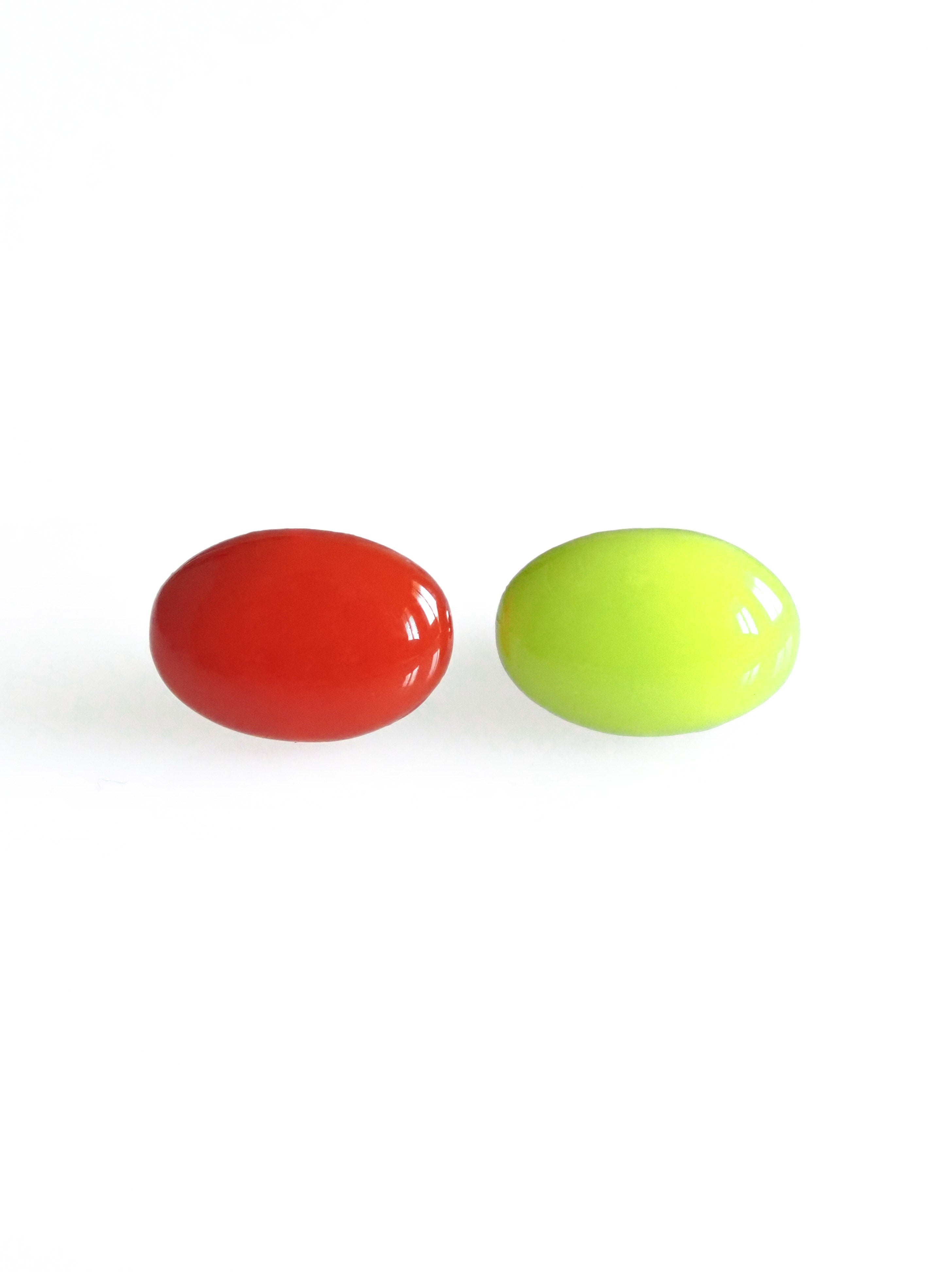 Solo resin stud earrings from the Chroma collection in red and electric lichen on a white background