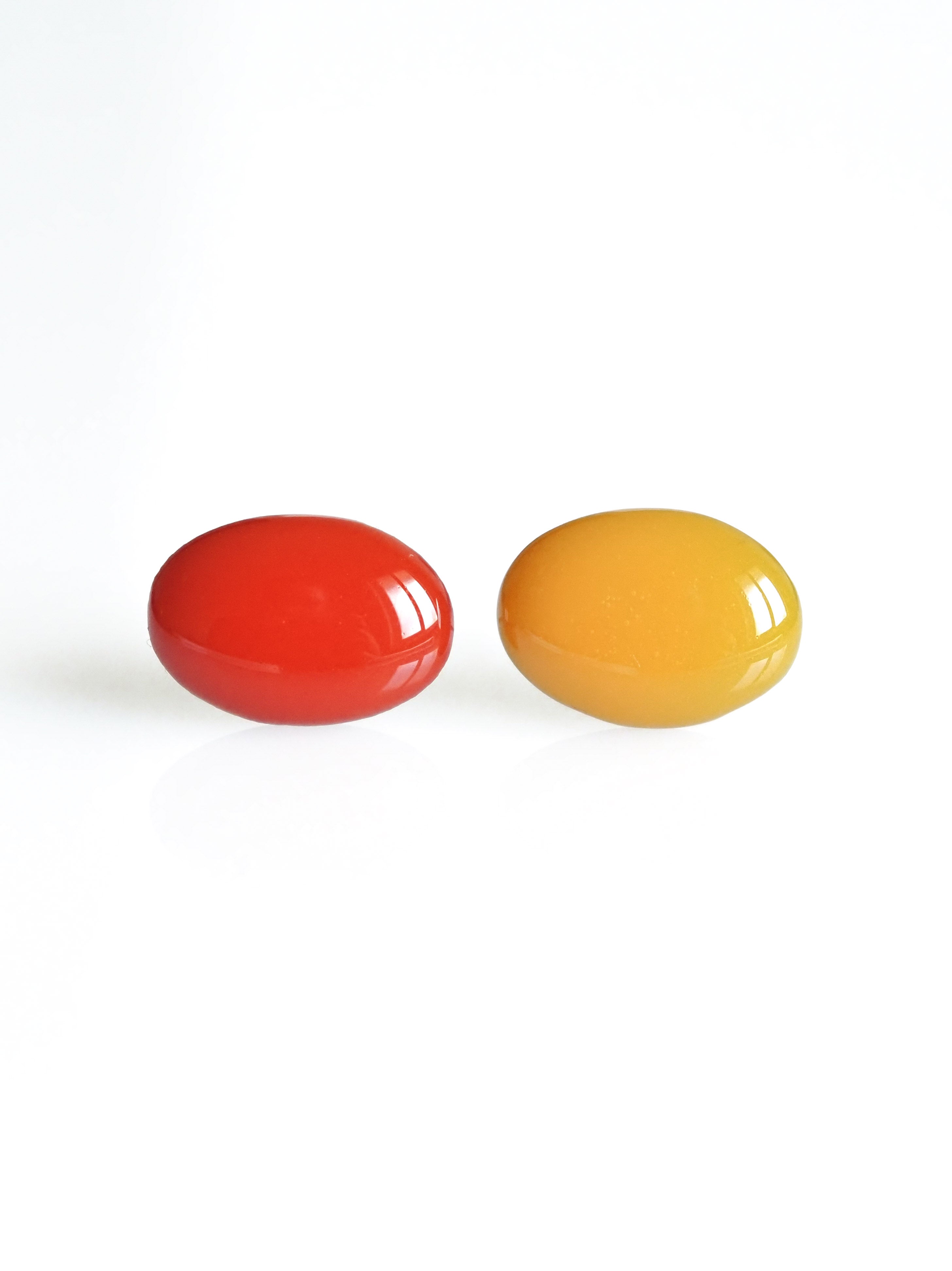 Solo resin stud earrings from the Chroma collection in red and marigold yellow on a white background