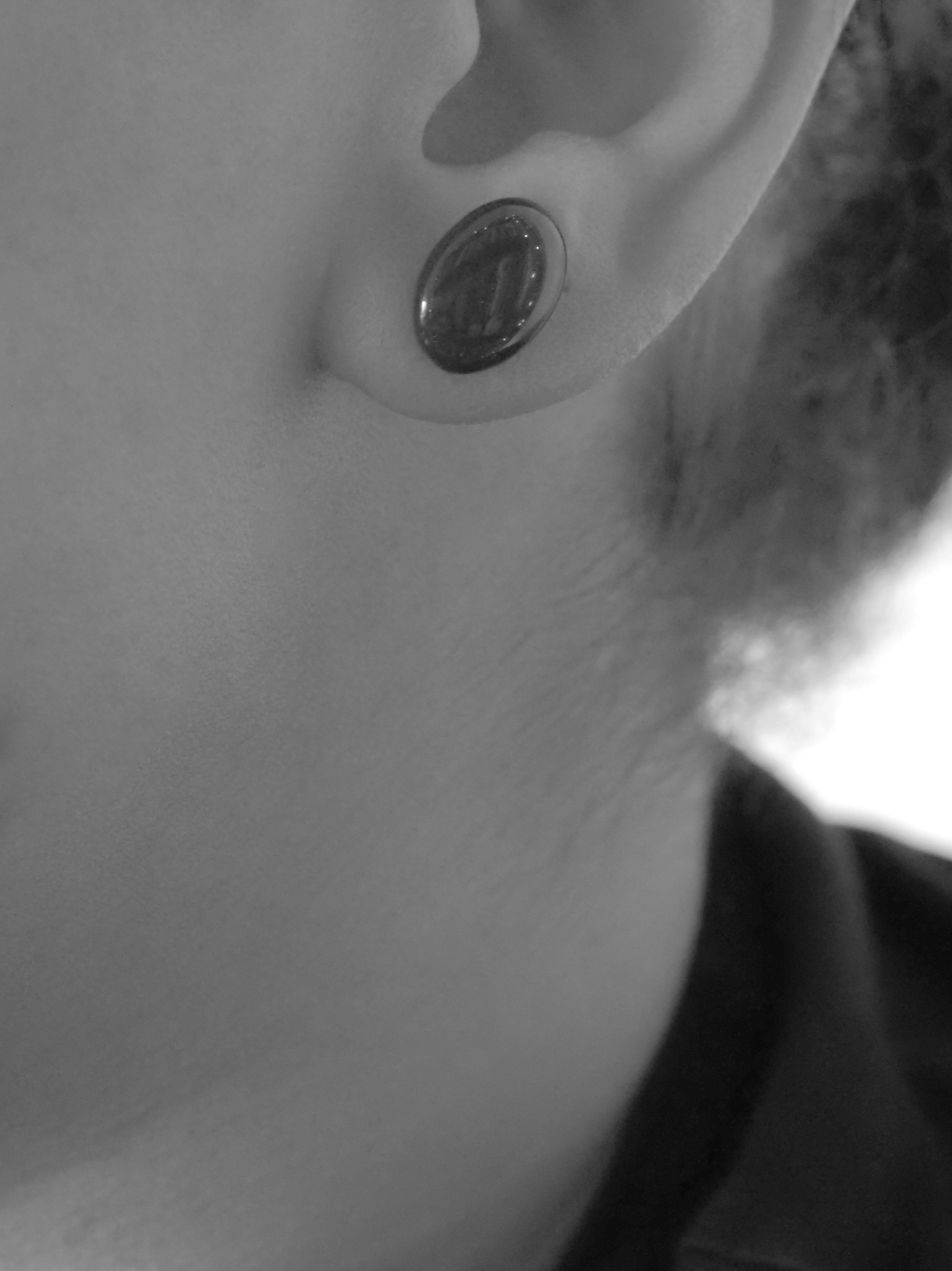 Close cropped greyscale image of the handmade Solo stud earrings being worn.